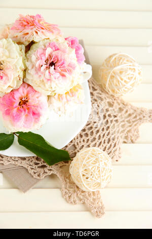 Le Rose in coppa su tovaglioli su sfondo di legno Foto Stock
