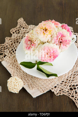 Le Rose in coppa su tovaglioli su sfondo di legno Foto Stock