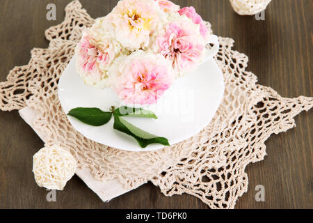 Le Rose in coppa su tovaglioli su sfondo di legno Foto Stock