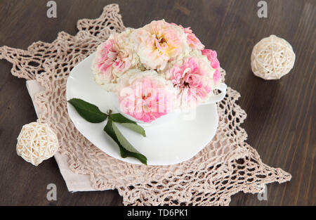 Le Rose in coppa su tovaglioli su sfondo di legno Foto Stock