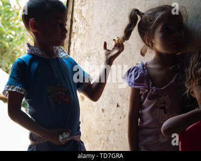 Caracas, Venezuela. 8 Giugno, 2019. Petare è la più grande baraccopoli di Caracas Venezuela. Due cugini di condividere un momento come si gioca con un altro dei capelli. Ci sono 11 persone che vivono in questa due room home. Sono loro a vivere con la loro nonna, e altri cugini come i loro genitori hanno lasciato per la Colombia per fare soldi da inviare a casa. Con le speranze di eventally invio per loro e per i loro figli. Credito: Allison cena/ZUMA filo/Alamy Live News Foto Stock