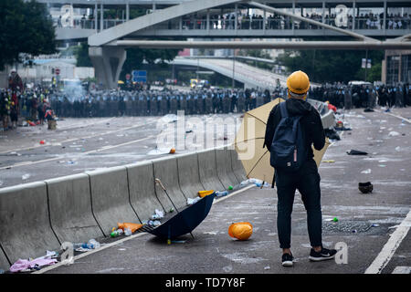 Hong Kong. 12 Giugno, 2019. Un manifestante con ombrello si trova in prima linea durante gli scontri con la polizia. Migliaia di manifestanti hanno occupato le strade vicino al consiglio legislativo complesso in Hong Kong per chiedere al governo di ritirare la legge in materia di estradizione. Il governo di Hong Kong ha rifiutato di ritirare o ritardo di avanzare la bill dopo decine di migliaia di persone hanno marciato contro di essa la domenica. Credito: SOPA Immagini limitata/Alamy Live News Foto Stock