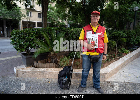 Athens, Athens, Grecia. 12 Giugno, 2019. Michael, 72, uno dei Shedia di venditori ambulanti, sorride alla telecamera con una copia di Shedia durante il tour ufficiale.Il tour di ''˜invisibile di Atene è organizzato da Shedia e va in pezzi di Atene che i locali ritengono di essere pericolose aree della città e sono generalmente evitati dai turisti. Shedia è il solo greco street giornale. Il tour prevede che mostra le condizioni dei senzatetto in Atene. Il Ministero greco della solidarietà sociale stima che vi sono stati più di 1.500 senzatetto per le strade di Atene nel 2018. (Credito immagine: Foto Stock