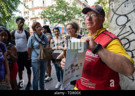 Athens, Athens, Grecia. 12 Giugno, 2019. Michael, 72, uno dei Shedia di venditori ambulanti, mostra una copia di Shedia ai partecipanti del tour invisibile.Il tour di ''˜invisibile di Atene è organizzato da Shedia e va in pezzi di Atene che i locali ritengono di essere pericolose aree della città e sono generalmente evitati dai turisti. Shedia è il solo greco street giornale. Il tour prevede che mostra le condizioni dei senzatetto in Atene. Il Ministero greco della solidarietà sociale stima che vi sono stati più di 1.500 senzatetto per le strade di Atene nel 2018. (Credito Immagine: © Lexie Foto Stock