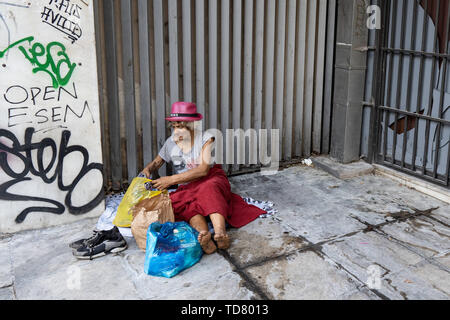 Athens, Athens, Grecia. 12 Giugno, 2019. Una donna senzatetto con sacchetti di plastica e scarpe per le strade di Atene durante il tour ufficiale.Il tour di ''˜invisibile di Atene è organizzato da Shedia e va in pezzi di Atene che i locali ritengono di essere pericolose aree della città e sono generalmente evitati dai turisti. Shedia è il solo greco street giornale. Il tour prevede che mostra le condizioni dei senzatetto in Atene. Il Ministero greco della solidarietà sociale stima che vi sono stati più di 1.500 senzatetto per le strade di Atene nel 2018. (Credito Immagine: © Lexie Harrison-C Foto Stock