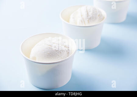 Riga di carta coppe di gelato alla vaniglia su sfondo blu. Foto Stock