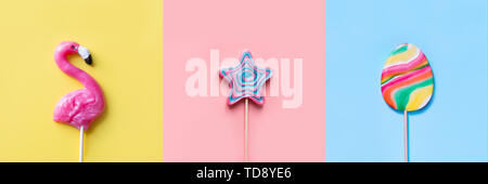 Tre lecca lecca colorati candy come cuore e di turbolenza sul blu e rosa. Strano concetto. Vista dall'alto. Collage. Foto Stock