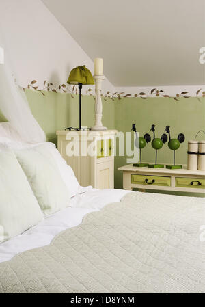 Uccelli in legno decorazione su bastoni sul basso tavolino accanto al letto matrimoniale con cuscini e tendina in mansarda camera da letto NEL REGNO UNITO E IN IRLANDA A DESTRA Foto Stock