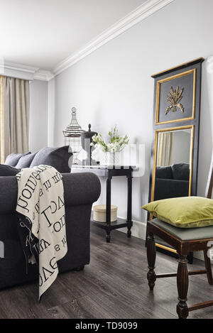 Specchio in cornice di legno con elementi gilted in piedi dietro il divano in soggiorno spazioso UK & IRISH UTILIZZARE SOLO Foto Stock