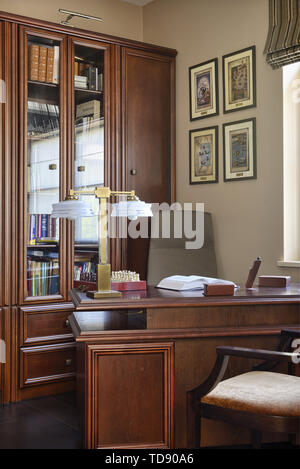 Vintage scacchiera e libro aperto sulla scrivania in piedi di fronte ad armadio alto con sportello in vetro nella sala di studio NEL REGNO UNITO E IN IRLANDA I DIRITTI SOLTANTO Foto Stock