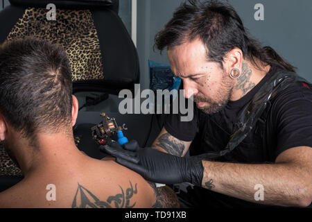 Tattooist facendo un tatuaggio su un client del braccio Foto Stock