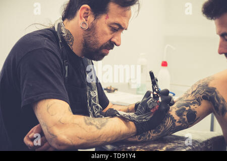 Tattooist facendo un tatuaggio su un client del braccio Foto Stock