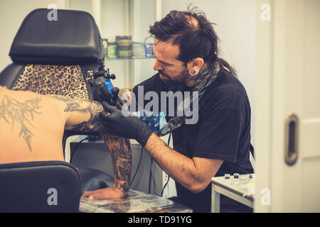 Tattooist facendo un tatuaggio su un client del braccio Foto Stock
