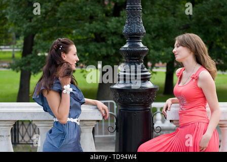 Ritratto di due belle giovani donne in parco e parlare con sorrisi felici. Amici donne attraenti di successo che chiacchierano nel parco Foto Stock