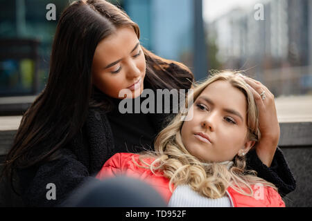 Giovane donna consolante triste amico in città Foto Stock