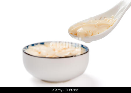 Cucchiaio tenuto fuori tofu jelly bianco sul tracciato di ritaglio Foto Stock