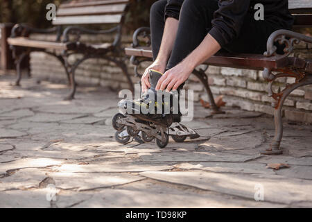 Un giovane di gambe in shot, mettendo su pattini a rotelle in linea. Foto Stock