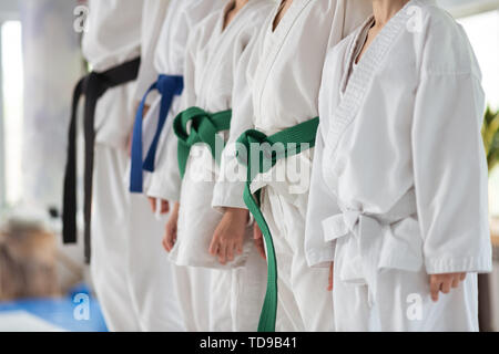 Prima di partecipare al corso di formazione. Bambini indossare nastri colorati in piedi vicino al trainer con la cintura nera Foto Stock