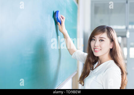 Bella ragazza giovane con lavagna verde in aula Foto Stock