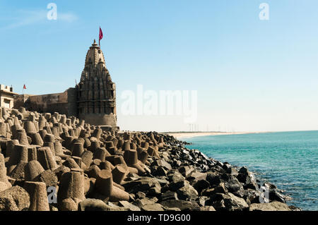 Lone tempio indù con bandiera sul mare Arabico costa con interruttori di onda Foto Stock