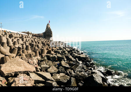 Lone tempio indù con bandiera sul mare Arabico costa con interruttori di onda Foto Stock