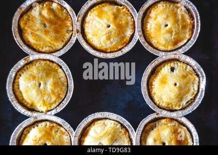 Chiuso mini quiche quiche farcite con carne e funghi, frutti, ciliegie su uno sfondo scuro. vista dall'alto. Foto Stock