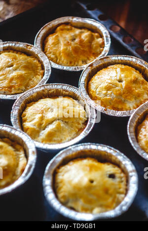 Chiuso mini quiche quiche farcite con carne e funghi, frutti, ciliegie su uno sfondo scuro. vista dall'alto. Foto Stock