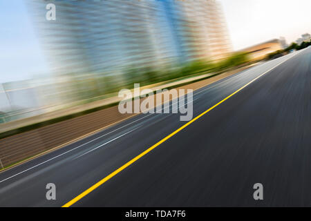 Svuotare strada asfaltata e sfocate degli edifici Foto Stock
