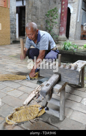 (190614) -- YUDU, 14 giugno 2019 (Xinhua) -- sandali di paglia artigiano Xiao Nandou dimostra il processo per rendere sandali di paglia nel villaggio di Hanxin, Yudu County della Cina dell'est della provincia di Jiangxi, 13 giugno 2019. Xiao Nandou, 75 anni, è uno dei pochi artigiani in grado di armatura sandali di paglia in Yudu County. Suo padre, anche un sandalo di paglia artigiano, usato per tessere 200 coppie di sandali di paglia insieme con altri abitanti del villaggio in un paio di giorni per l'esercito rosso i soldati in partenza per la lunga marcia, una manovra militare effettuata dai cinesi dei lavoratori e contadini' Armata Rossa dal 1934 al 1936. (Xinhua/Zhou Mi) Foto Stock