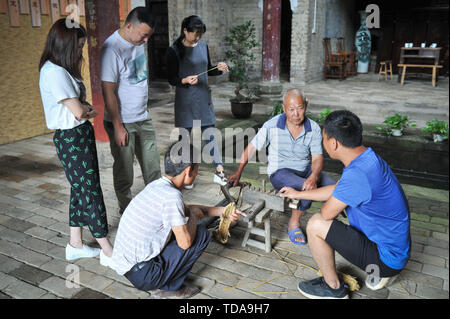 (190614) -- YUDU, 14 giugno 2019 (Xinhua) -- sandali di paglia artigiano Xiao Nandou colloqui con la gente del posto nel villaggio di Hanxin, Yudu County della Cina dell'est della provincia di Jiangxi, 13 giugno 2019. Xiao Nandou, 75 anni, è uno dei pochi artigiani in grado di armatura sandali di paglia in Yudu County. Suo padre, anche un sandalo di paglia artigiano, usato per tessere 200 coppie di sandali di paglia insieme con altri abitanti del villaggio in un paio di giorni per l'esercito rosso i soldati in partenza per la lunga marcia, una manovra militare effettuata dai cinesi dei lavoratori e contadini' Armata Rossa dal 1934 al 1936. (Xinhua/Li Renzi) Foto Stock