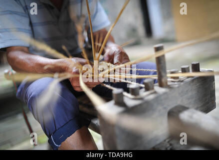 (190614) -- YUDU, 14 giugno 2019 (Xinhua) -- sandali di paglia artigiano Xiao Nandou opere su sandali di paglia nel villaggio di Hanxin, Yudu County della Cina dell'est della provincia di Jiangxi, 13 giugno 2019. Xiao Nandou, 75 anni, è uno dei pochi artigiani in grado di armatura sandali di paglia in Yudu County. Suo padre, anche un sandalo di paglia artigiano, usato per tessere 200 coppie di sandali di paglia insieme con altri abitanti del villaggio in un paio di giorni per l'esercito rosso i soldati in partenza per la lunga marcia, una manovra militare effettuata dai cinesi dei lavoratori e contadini' Armata Rossa dal 1934 al 1936. (Xinhua/Li Renzi) Foto Stock