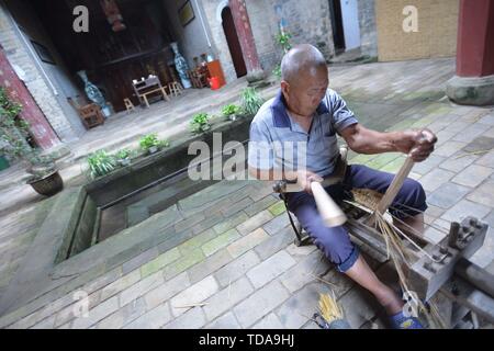 (190614) -- YUDU, 14 giugno 2019 (Xinhua) -- sandali di paglia artigiano Xiao Nandou opere su sandali di paglia nel villaggio di Hanxin, Yudu County della Cina dell'est della provincia di Jiangxi, 13 giugno 2019. Xiao Nandou, 75 anni, è uno dei pochi artigiani in grado di armatura sandali di paglia in Yudu County. Suo padre, anche un sandalo di paglia artigiano, usato per tessere 200 coppie di sandali di paglia insieme con altri abitanti del villaggio in un paio di giorni per l'esercito rosso i soldati in partenza per la lunga marcia, una manovra militare effettuata dai cinesi dei lavoratori e contadini' Armata Rossa dal 1934 al 1936. (Xinhua/Zhou Mi) Foto Stock