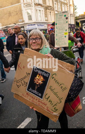 Londra, Regno Unito. 14 giugno 2019. Migliaia a piedi in silenzio da vicino alla Torre Grenfell ricordando le vittime del disastro nel secondo anniversario del disastroso incendio che ha ucciso 72 e lasciato superstiti traumatizzati. Le promesse fatte di Theresa Maggio e a Kensington & Chelsea consiglio non sono state mantenute e dell'inchiesta sembra essere semplicemente fornendo un pretesto per l'inerzia. Credito: Peter Marshall / Alamy Live News Foto Stock