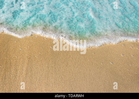 Morbide onde blu con schiuma di mare sulla spiaggia sabbiosa sfondo. Foto Stock