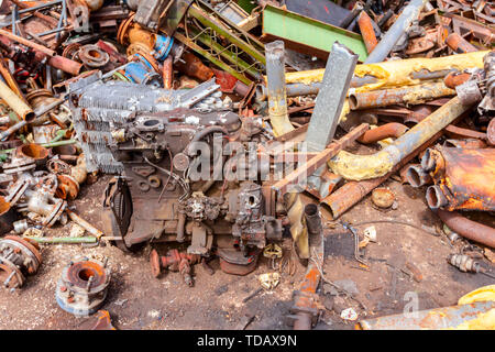 Età compresa tra motore a combustione interna è collocato tra le parti arrugginite di apparecchiature obsolete in complesso industriale. Foto Stock