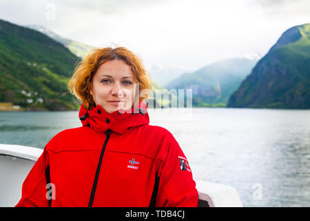 I capelli rossi freckled giovane donna in giacca rossa. Foto Stock