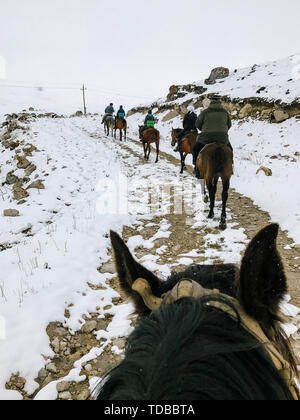 In sella ad un cavallo dalla prima persona e apertura di una recensione su altri piloti in inverno in montagna Foto Stock