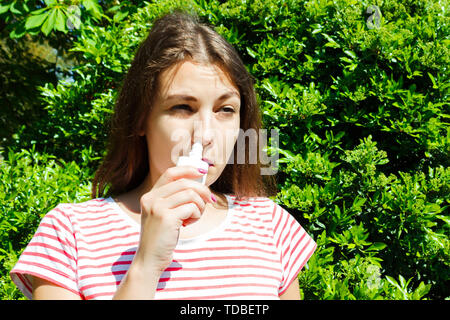 Ragazza gocciolamenti naso chiuso da allergia. Donna con Apparato Respiratorio Spray per naso in fioritura primaverile. Ritratto di una donna con problemi respiratori da un Foto Stock