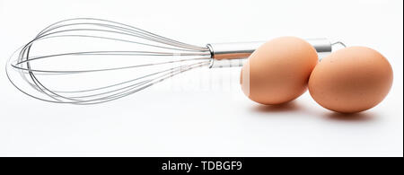 Cucina metallica aste manualmente per la miscelazione di prodotti alimentari con 2 uova fresche (collezione di oggetti da cucina). Isolato su sfondo bianco. Foto Stock