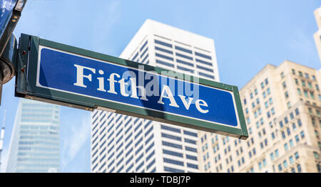 Fifth Ave strada segno, Manhattan New York downtown. Segno blu su blur facciata degli edifici e il cielo blu, sfondo Foto Stock