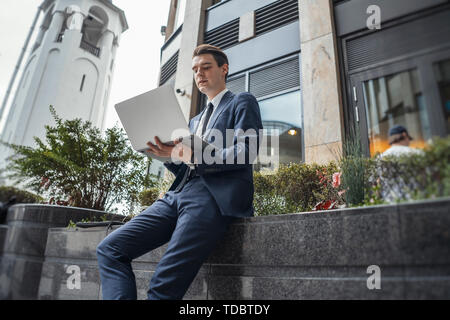 Close up di imprenditore lavora su un computer portatile accanto al centro affari ed il grattacielo presso il centro cittadino. Foto Stock