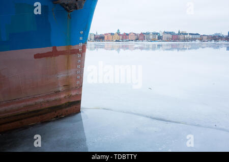 Vista invernale di Kungsholmen, Stoccolma guardando attraverso il lago ghiacciato con barche ormeggiate in primo piano. Foto Stock