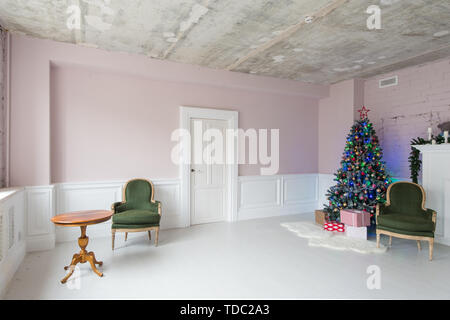 Eleganti interni di natale con una poltrona vintage, camino e una tabella. Foto Stock