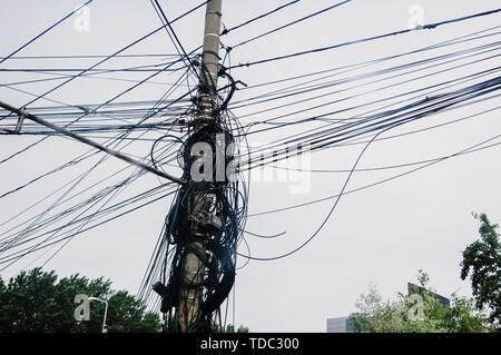 Palo di legno pieno di fili di telefono aggrovigliato insieme, concetto di telecomunicazione. Foto Stock