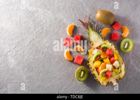 Frutta Mix servita all'interno di ananas su sfondo grigio Foto Stock