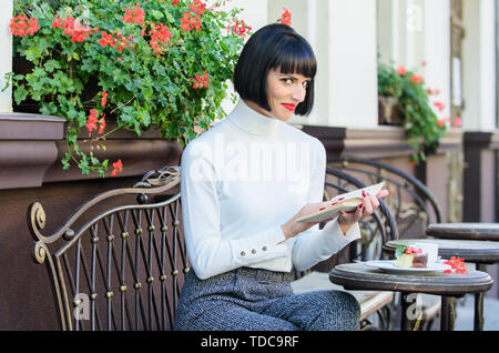 La letteratura per femmina. Ragazza bere il caffè leggere il libro. La tazza di un buon caffè e libro piacevole combinazione migliore per un perfetto fine settimana. Miglioramento di auto concetto. La donna bere godono di un buon libro cafe terrazza. Foto Stock