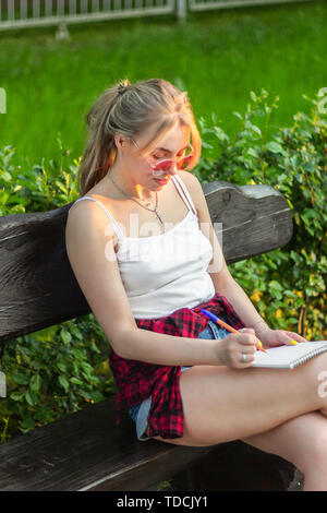 Ragazza scrittore scuola attira park Foto Stock