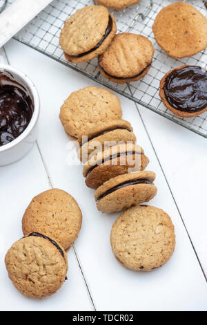 In casa kingston biscotti. Australian biscotto. Round di cocco e avena biscotti frollini con crema di cioccolato in medio Foto Stock