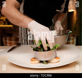 Professopnal chef è la cottura di antipasto con capesante Foto Stock