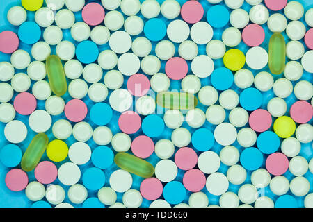 Colorato di bianco, rosa blu, giallo e verde pillole e compresse. Medico di fondo. Foto Stock